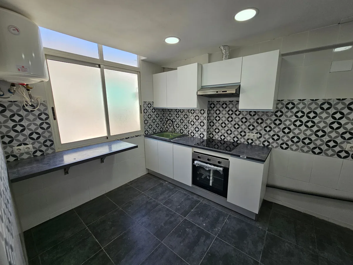 Cocina terminada con muebles blancos, encimera oscura y salpicadero hidráulico