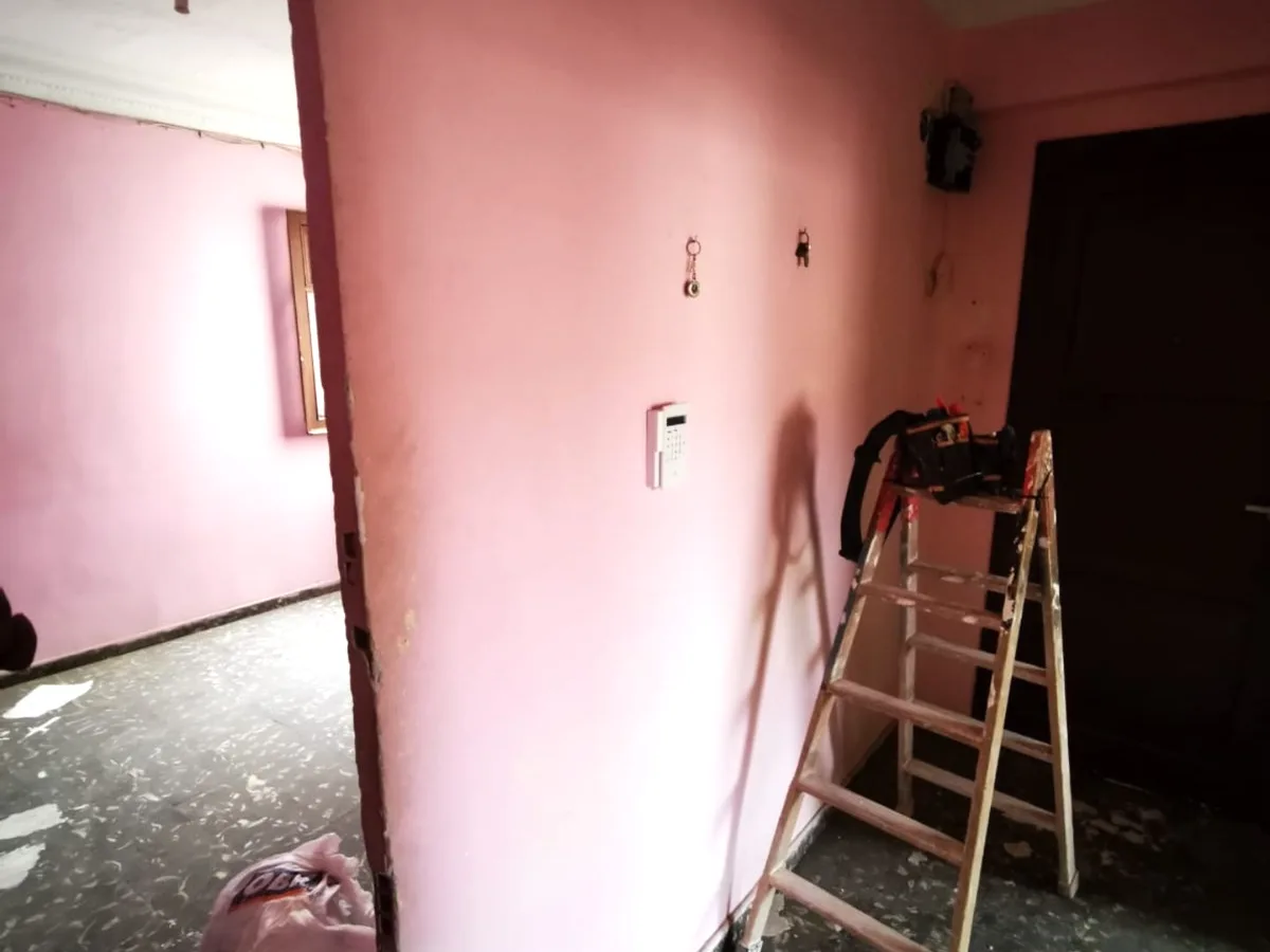 Salón antes de la reforma: paredes originales, puerta antigua y suelo levantado en obra