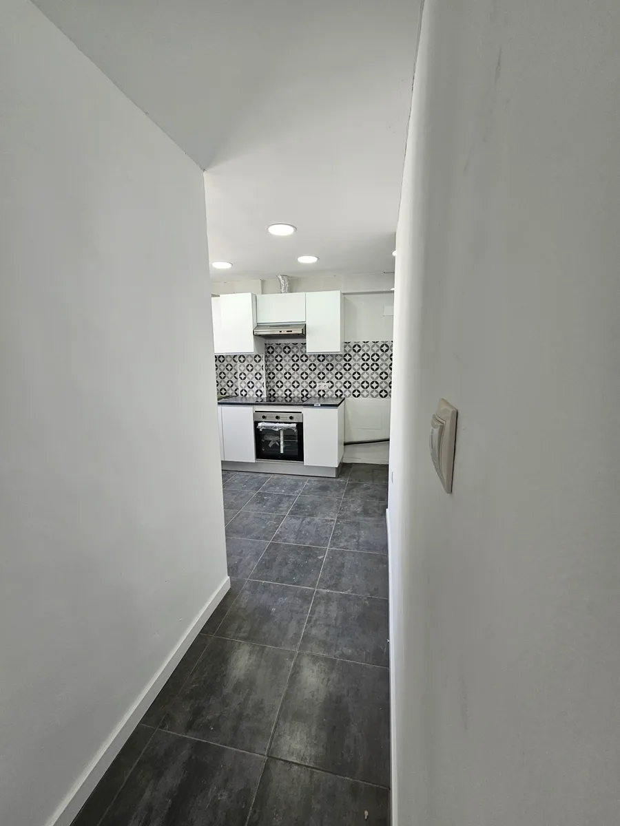 Paso hacia la cocina con suelo porcelánico gris y paredes recién pintadas